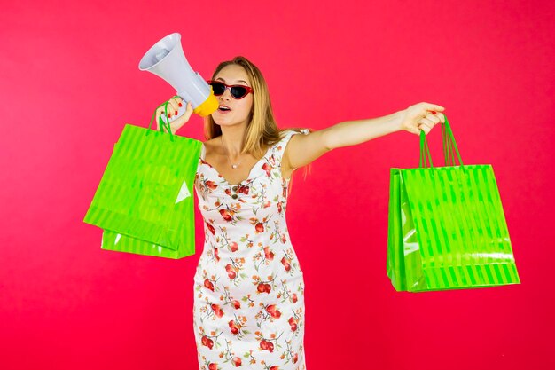 Femme avec des sacs à provisions criant sur mégaphone