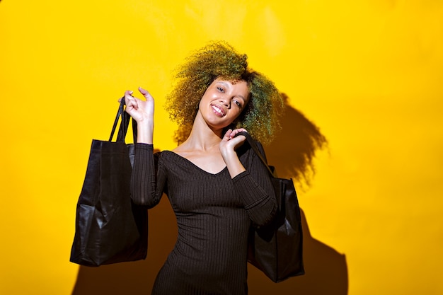 Femme avec des sacs à provisions sur fond jaune shopping concept