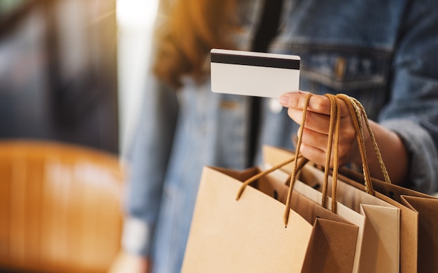 Une femme avec des sacs à provisions tenant et utilisant une carte de crédit pour l'achat