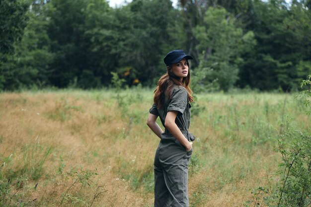 Femme en salopette forestière et casquette bleue sur la tête paysage d'été