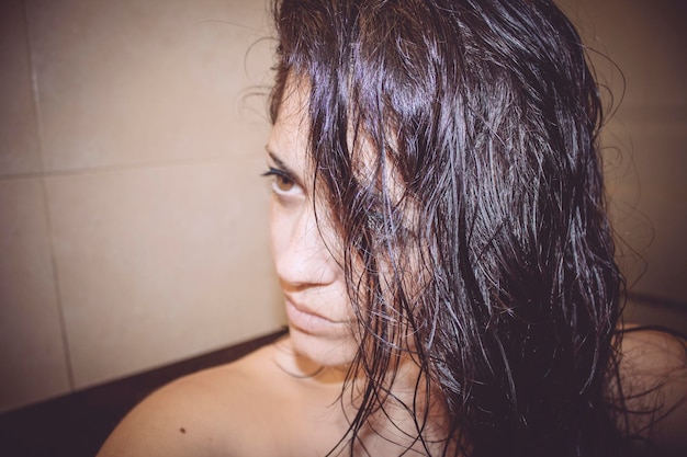 Photo femme sans chemise avec les cheveux mouillés regardant loin dans la salle de bain