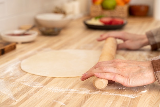 Femme Sans Visage Rouler La Pâte Avec Un Rouleau à Pâtisserie Sur La Table De Cuisine à La Maison,