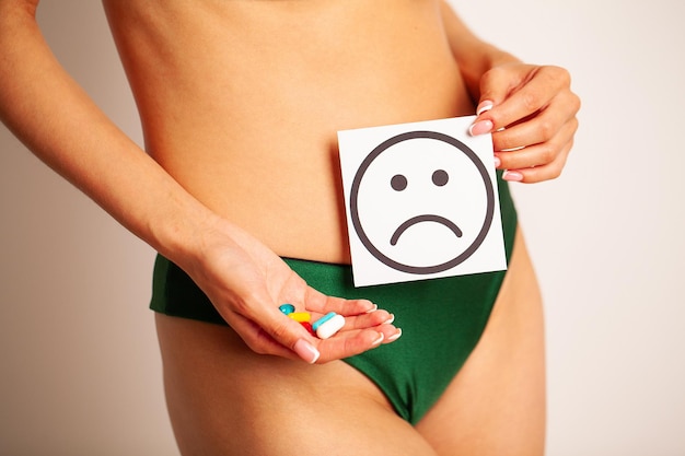 Femme santé corps féminin tenant une carte blanche sourire triste près de l'estomac en bonne santé