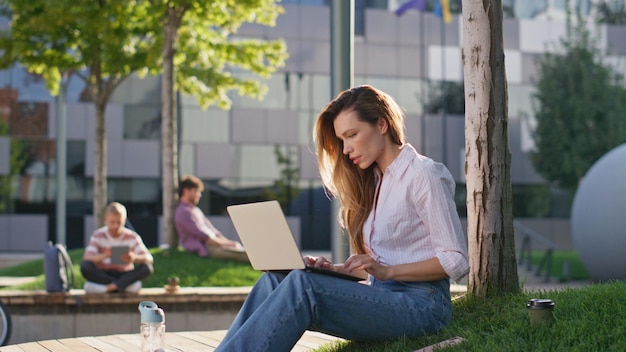 Une femme satisfaite termine son travail dans un parc de la ville. Une fille souriante ferme les yeux.