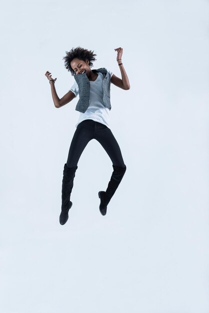 Femme sautant en l'air devant un fond gris