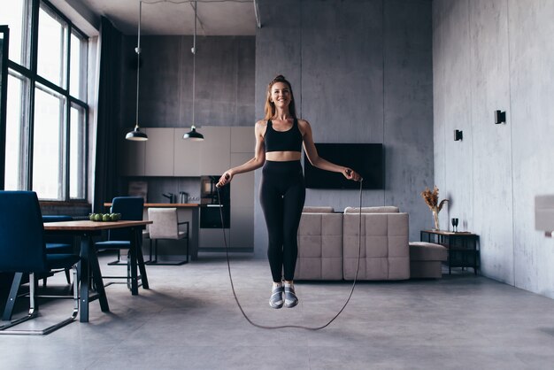 Femme sautant avec corde à sauter à la maison.