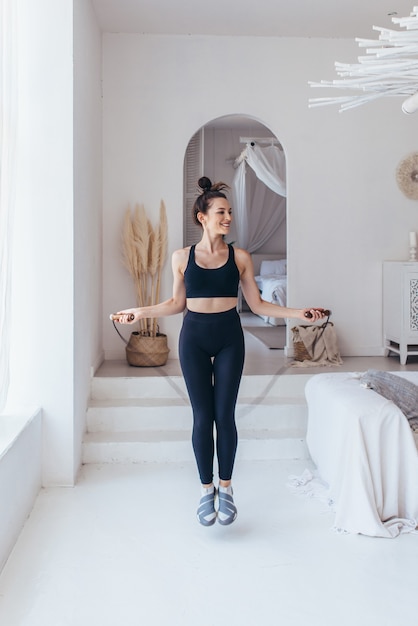 Femme sautant avec corde à sauter à la maison.