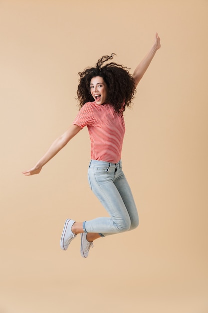 Femme sautant isolé sur mur beige.