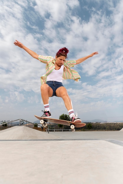 Femme sautant avec skateboard full shot