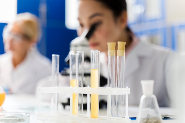 Photo femme scientifique défocalisée dans le laboratoire à l'aide d'un microscope