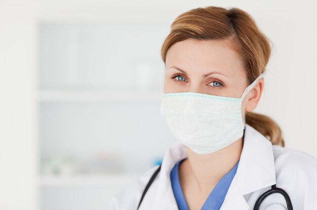 Femme scientifique avec un masque et un stéthoscope posant