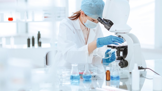 Femme scientifique regardant à travers un microscope