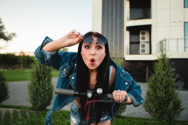 Femme avec scooter électrique sur la rue de la ville