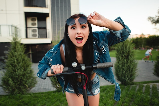 Femme avec scooter électrique sur la rue de la ville