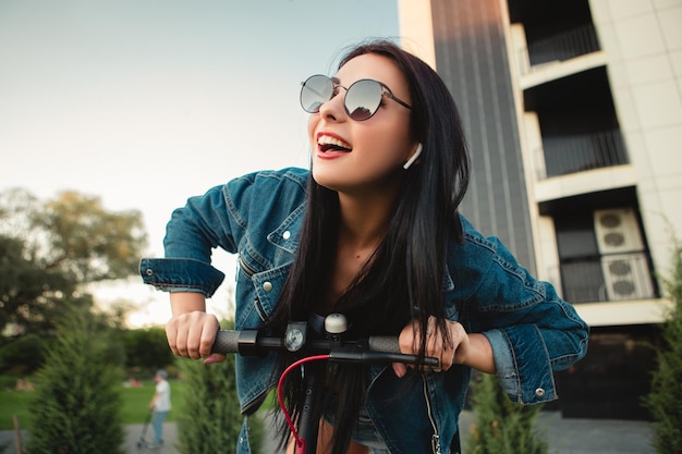 Femme avec scooter électrique sur la rue de la ville