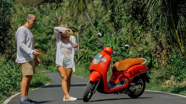 Femme sur un scooter rouge en vêtements blancs en voiture sur un sentier forestier Voyage dansant