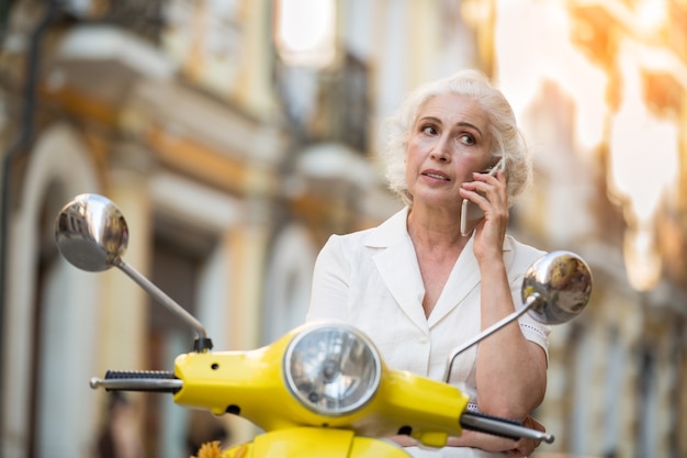 Femme sur scooter avec téléphone.