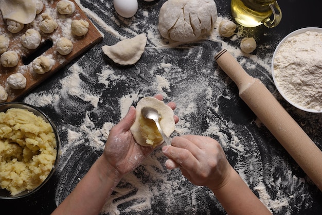 Femme sculpte des boulettes avec des pommes de terre à la main sur un fond noir tourné à partir de l'angle supérieur de la cuisine folklorique ukrainienne