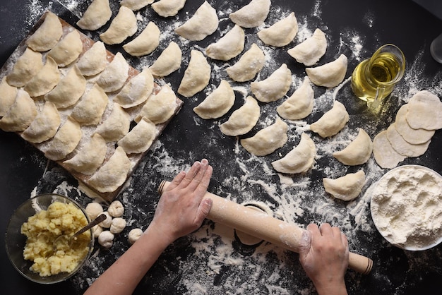 Femme sculpte des boulettes avec des pommes de terre à la main sur un fond noir tourné à partir de l'angle supérieur de la cuisine folklorique ukrainienne