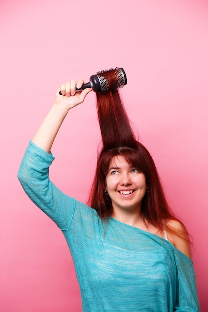 Femme se brossant les cheveux sur fond rose