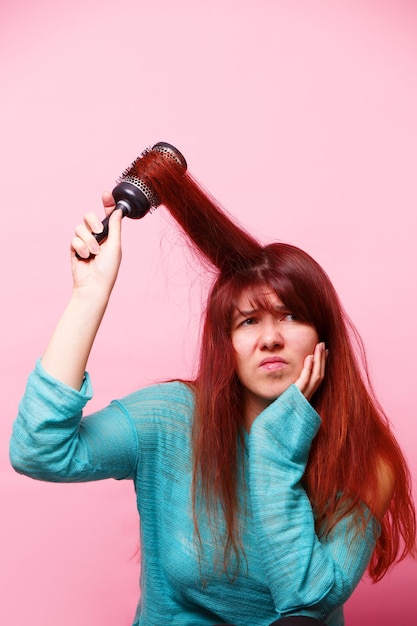 Femme se brossant les cheveux sur fond rose