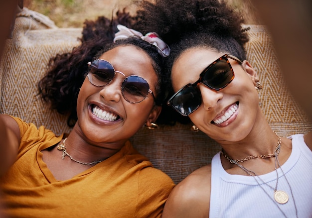 Une femme se détend et des amis sourient pour un selfie ensemble dans le bonheur avec des lunettes pour une amitié joyeuse Des femmes noires heureuses se détendent pour des vacances d'été ou une pause souriante pour une aventure amusante avec un ami