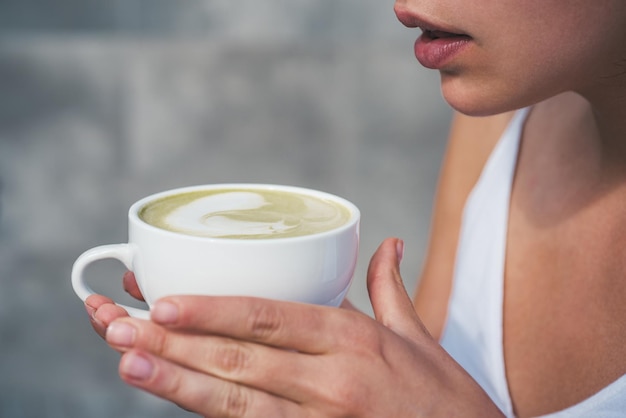 Une femme se détend au café et boit une cérémonie du thé matcha latte d'une fille matinale parfaite avec du café vert...