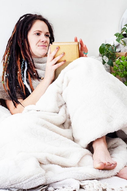 Photo une femme se détend dans des couvertures confortables en train de lire un livre dans un environnement paisible et tranquille