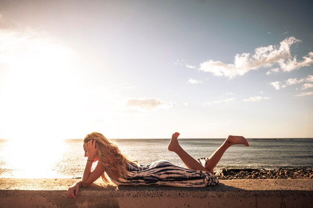 Une femme se détend sur la plage contre le ciel.