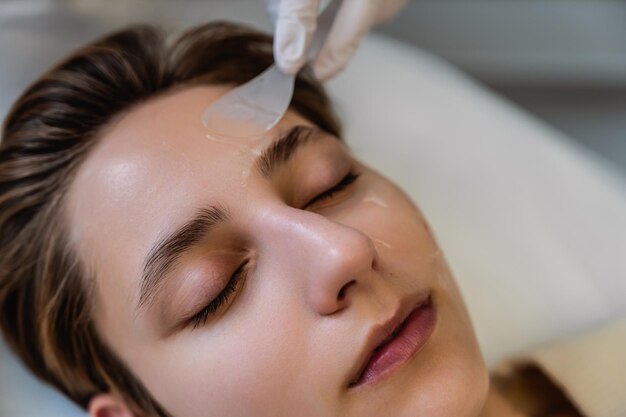 Une femme se détend en se faisant soigner le visage avec un outil cosmétique appliqué sur sa peau