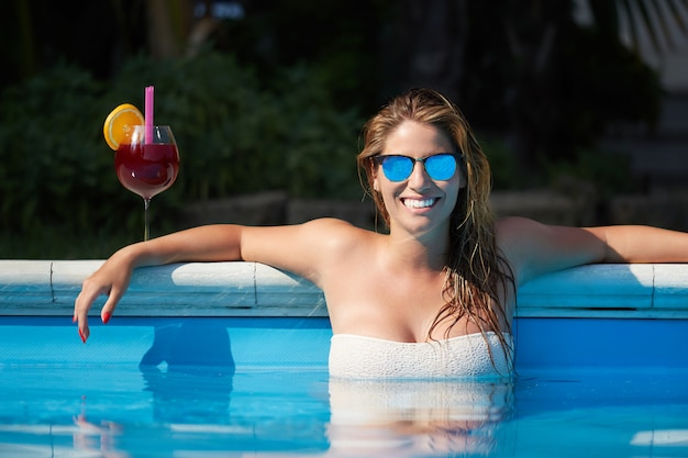 Femme se détendre et boire un cocktail à la piscine