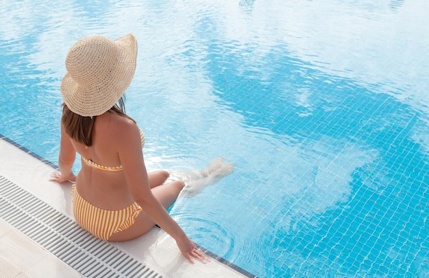 Femme se détendre dans la piscine pendant les vacances d'été Concept de vacances chaudes et ensoleillées avec espace de copie