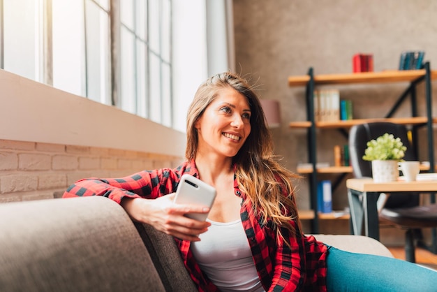 Femme se détendre à la maison pendant son temps libre avec un téléphone portable