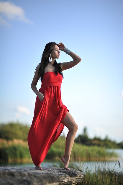 femme se détendre sur le sable en robe rouge