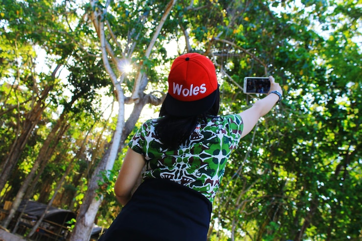 Photo une femme se fait un selfie avec son téléphone portable contre des arbres.