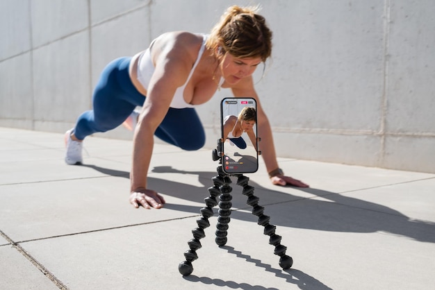 Une femme se filme sur son téléphone portable et diffuse en direct son entraînement de fitness sur les réseaux sociaux