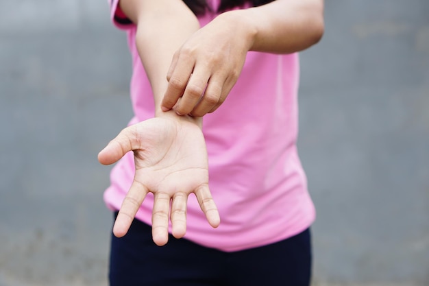 Photo femme se grattant le bras des démangeaisons sur fond gris clair la cause des démangeaisons de la peau comprend les piqûres d'insectesconcept de la peau des soins de santé