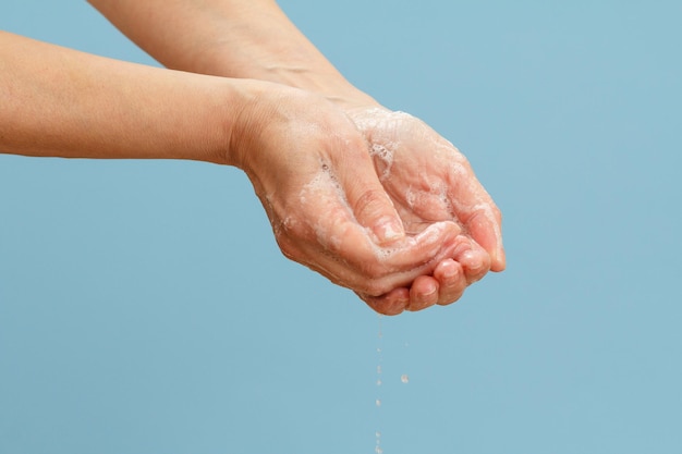 Femme se lavant les mains avec du savon sur fond bleu Se nettoyant correctement les mains