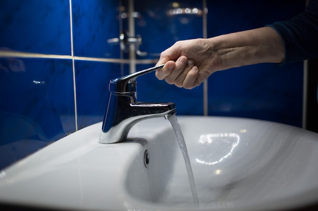 Femme se lave les mains avec du savon sous le robinet d'eau.