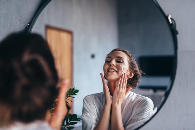 Femme se lave le visage avec de la mousse