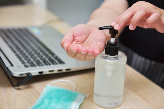 Femme se laver les mains avec un assainisseur d'alcool avant de commencer à travailler à la maison pour éviter la propagation de Covid-19