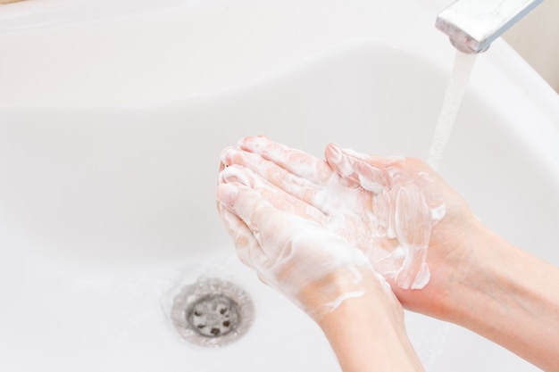 Femme se laver les mains sur le lavabo dans la salle de bain.