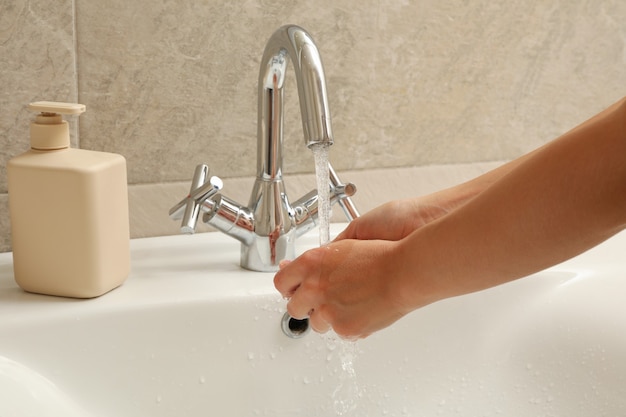 Femme se laver les mains sous le robinet d'eau dans l'évier