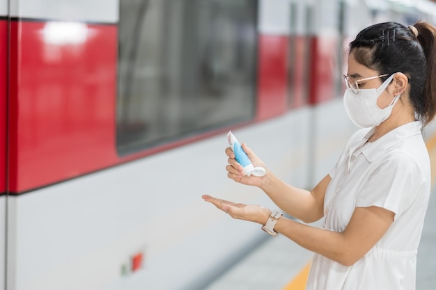 Une femme se nettoie la main avec un gel désinfectant à l'alcool dans le train ou les transports publics, protection Infection par la maladie à coronavirus. Hygiène personnelle, sécurité et transport de voyage selon les concepts COVID-19