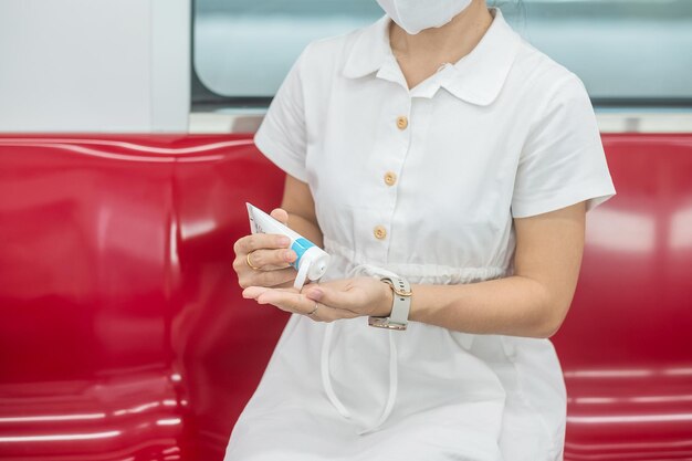 Une femme se nettoie la main avec un gel désinfectant à l'alcool dans le train ou les transports publics, protection Infection par la maladie à coronavirus. Hygiène personnelle, sécurité et transport de voyage selon les concepts COVID-19