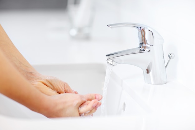 femme se nettoyant les mains dans la salle de bain