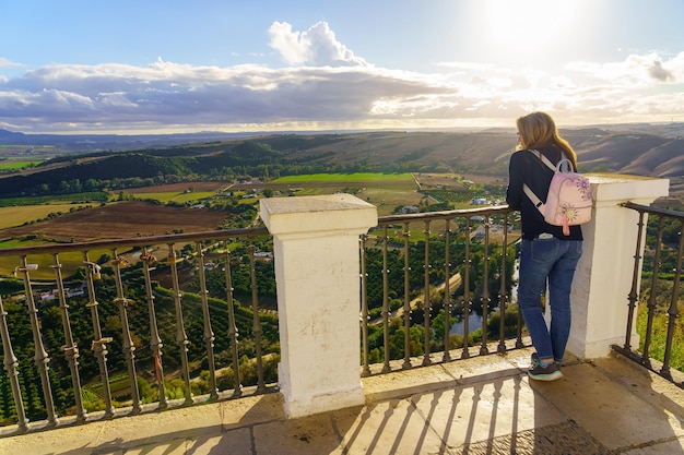 Femme se penchant à un point de vue et contemplant le paysage et le coucher du soleil à l'horizon Arcos de la Frontera Cadix