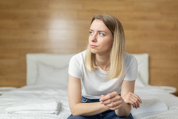 une femme se plaint d'un test de grossesse assis sur un canapé