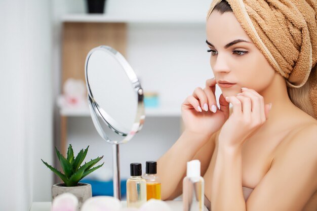 Femme se prépare pour le travail faisant le maquillage du matin dans le miroir de salle de bain à la maison