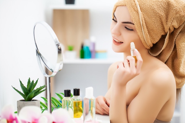 Femme se prépare pour le travail faisant le maquillage du matin dans le miroir de salle de bain à la maison